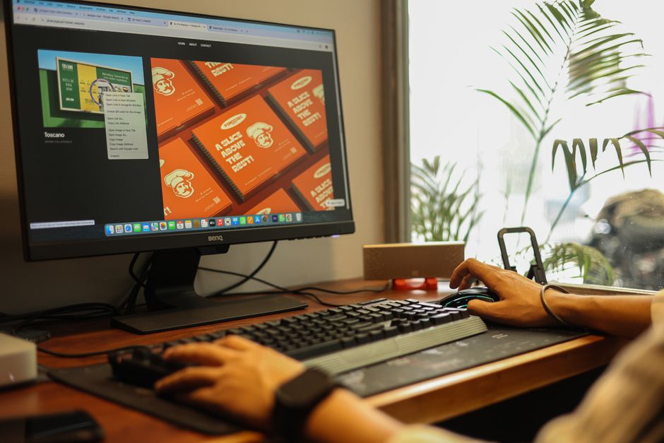 Mãos trabalhando em um computador em um escritório moderno, mostrando um ambiente focado e produtivo.