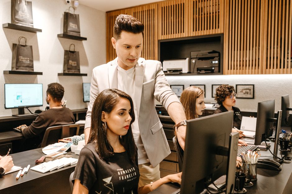 Equipe de uma agência web analisando dados e projetos em computadores, representando qualidade e transparência